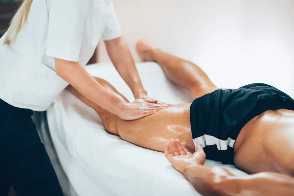 Therapist giving a sports massage to an athlete's leg.